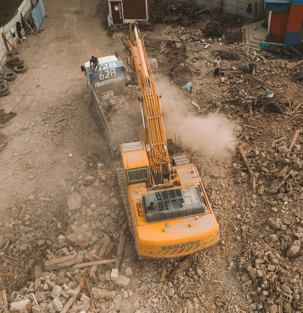 pexels photo 9373714 9373714 Aerial view of an excavator loading debris at a construction site with workers nearby.